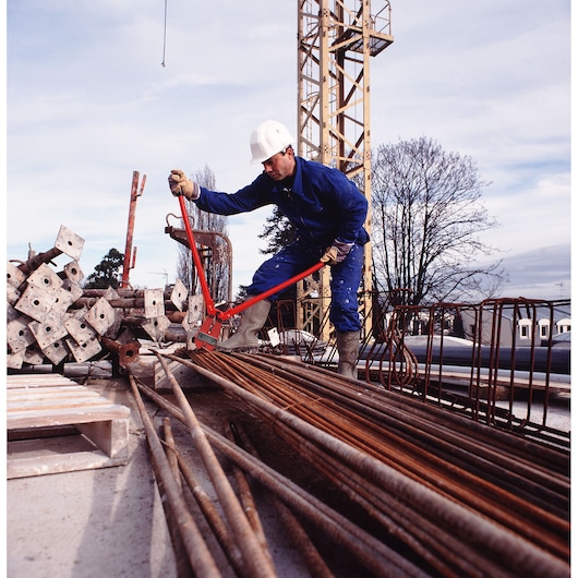 Facom 990B3 bolt cutter used by worker in blue uniform on construction site.