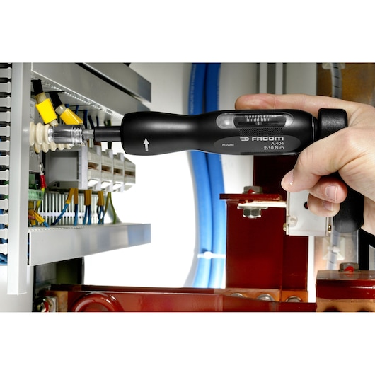 Photo of Facom A_300PA torque screwdriver used on an electrical panel by a hand.