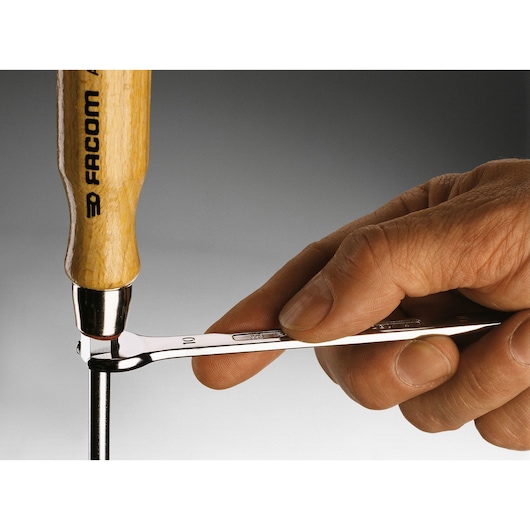 Photo of Facom ATHH_6_5X125 hand using wooden-handled hammer and wrench on metal rod.