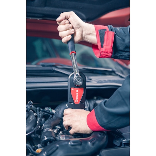 Facom AXS.LPB ratchet wrench used on car engine, close-up photography of tool in action.