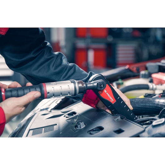 Facom AXS.LPB ratchet tool in use on car engine in workshop, close-up, photography.