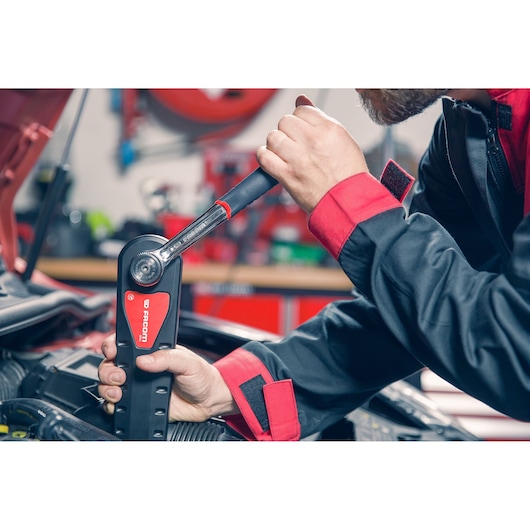 Photo of Facom AXS.SPB torque wrench being used by mechanic in workshop on car engine.