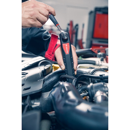 Photo of Facom digital torque wrench AXS.SPB used by mechanic on engine in workshop setting.