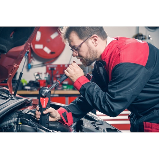 Facom AXS.SPB torque wrench used by mechanic in red and black uniform on car engine in workshop.