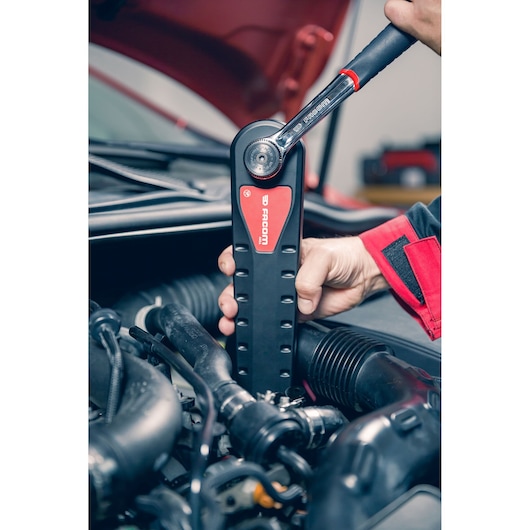 Facom AXS.SPB ratchet tool used by hand on car engine, close-up view.