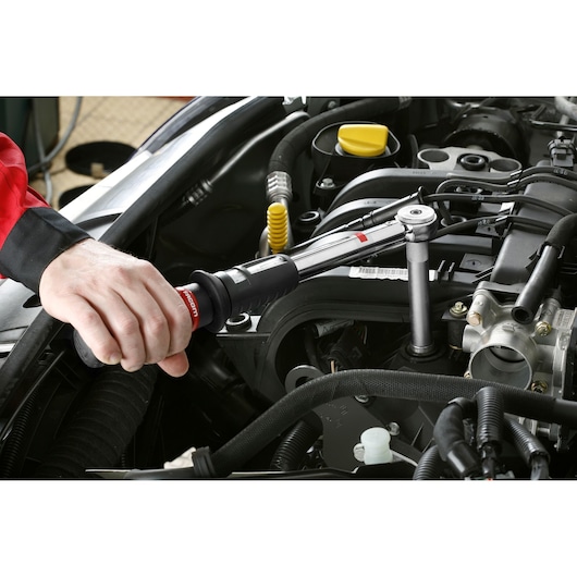 Facom BJ14BH2 torque wrench used on car engine, hand gripping black and red handle, automotive setting.