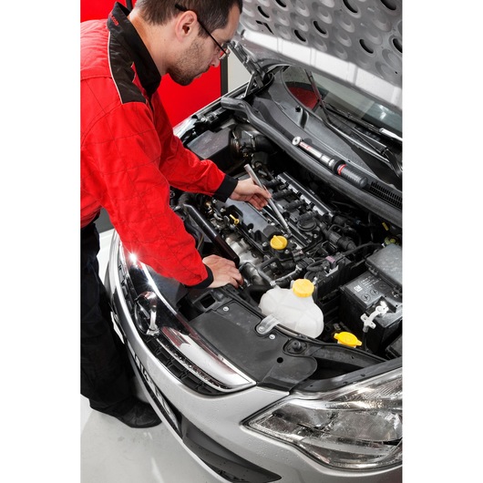 Facom BJ14BH2 photography of mechanic using tool under car hood, red and black uniform visible.