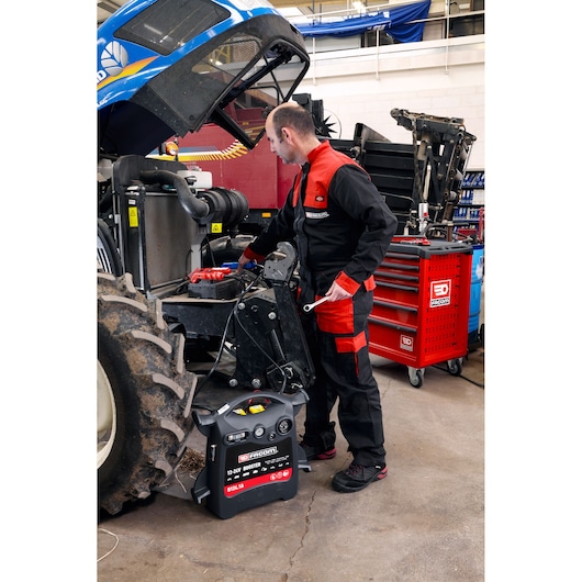Facom B124_1A booster pack in workshop setting with mechanic working on tractor near red tool chest.