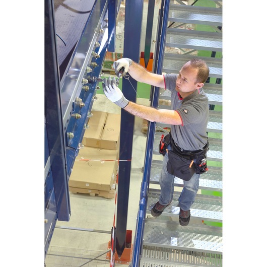 Photo of a worker on metal stairs using Facom BAG-RECT2SLS tool bag, wearing work gloves and tool belt.