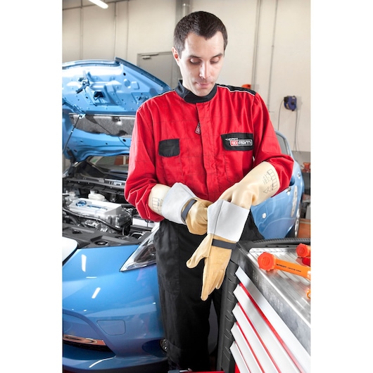 Facom BC_91VSE mechanic in red coveralls and protective gloves near open blue car hood, workshop setting.