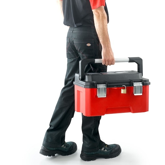 Photo of person carrying Facom BP.P20APB red and black toolbox with metal latches and lock, shown from the side.