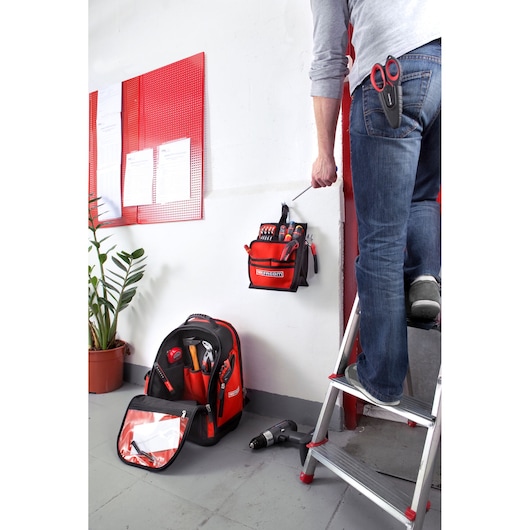 Facom BS.L30PB tool bag photography, red and black with tools, shown hanging on wall near ladder.