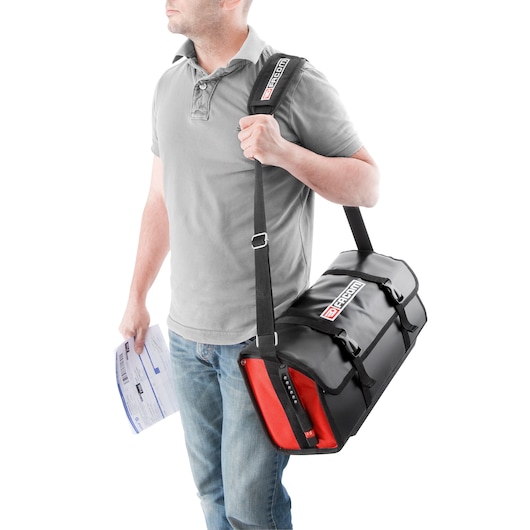 Photo of a person carrying a Facom BS.LMBCPB black and red tool bag with shoulder strap, side view.