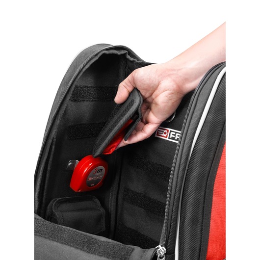 Photo of Facom BS.MCBPB tool bag interior with hand accessing internal pocket, red measuring tape secured inside.