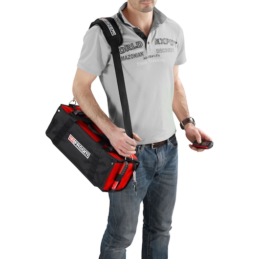 Facom BS.SMBPB black and red tool bag with shoulder strap, carried by person, front angle.