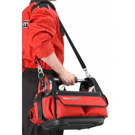 Facom BST14PB red tool bag with shoulder strap, carried by person, side view.