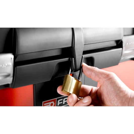 Photo of a hand locking a black Facom toolbox BT200 with a brass padlock, close-up angle.