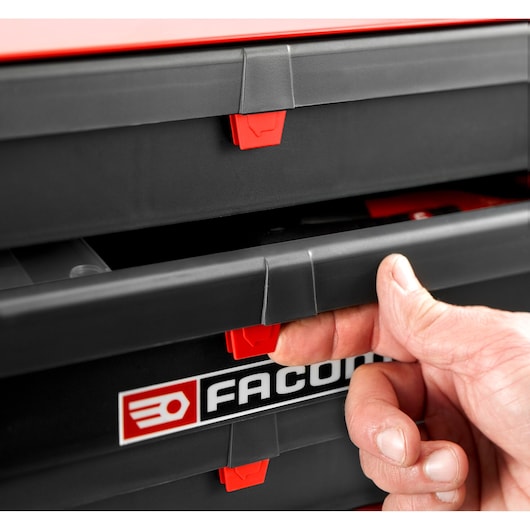 Photo of a hand opening a Facom BT203 black and red tool chest drawer, brand logo visible on front.