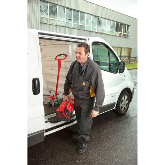 Facom BT9 red folding trolley held by worker beside white van, outdoor setting, photography.