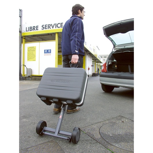 Facom BV_51A wheeled tool case being transported outdoors near a parked car, closed trunk visible.