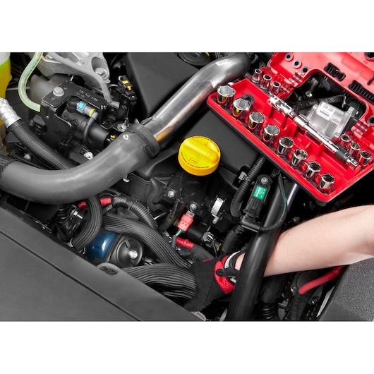 Facom socket set C48-2 on red tray used for automotive engine repair, mechanic's gloved hand visible.