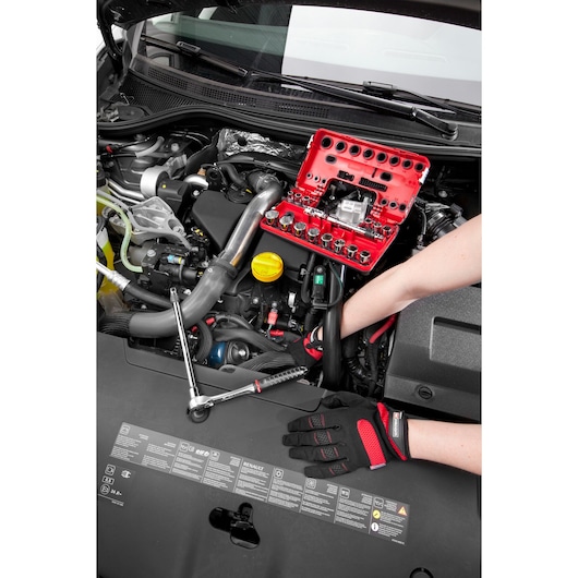 Facom C.48-J2PB socket set in red case on car engine during maintenance, mechanic's gloved hands visible.