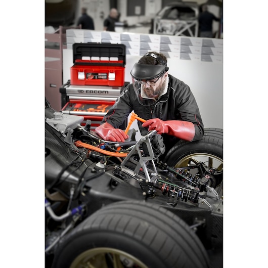 Photo of Facom CM.EPI1 technician in safety gear working on a car chassis with tool chest in background.