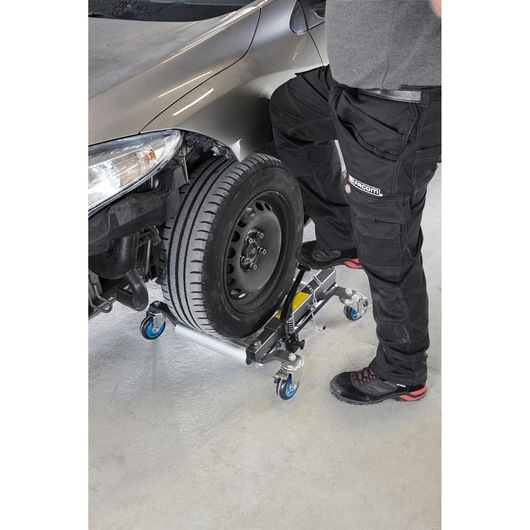Facom CR_12H wheel dolly in use, supporting a car tire with blue casters, side angle, workshop setting.