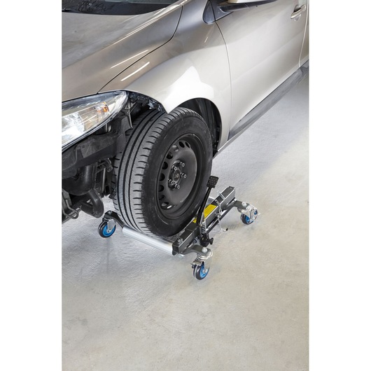 Facom CR_12H hydraulic wheel dolly with blue casters under a car front tire, angled view.
