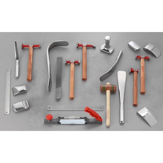 Facom CR_858J20 bodywork tool set with hammers, dollies, files, and shaping tools laid out on grey surface, top view.