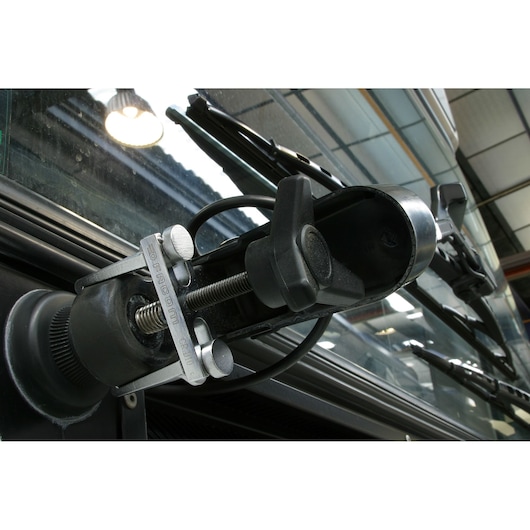 Facom CR_D10 windshield wiper puller tool mounted on a vehicle windshield, close-up view.