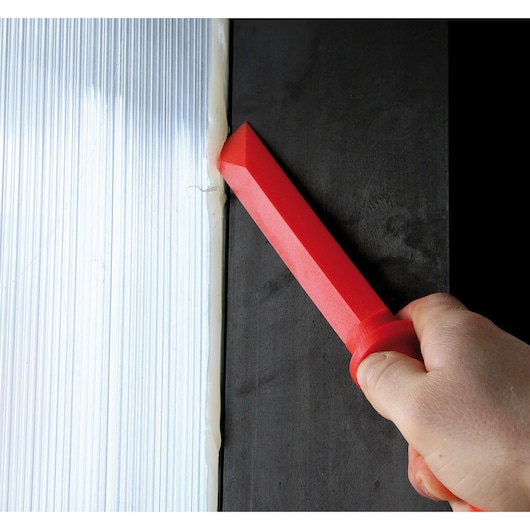 Facom CR.D4PB red plastic sealant tool used for smoothing caulk along metal and black surfaces.