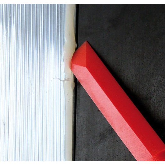 Photo of Facom CR.D4PB red chisel tool on black surface next to sealed edge with white caulk.
