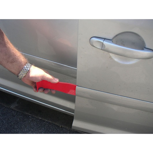 Facom CR.D5PB red plastic trim removal tool in use on a car door, side angle.