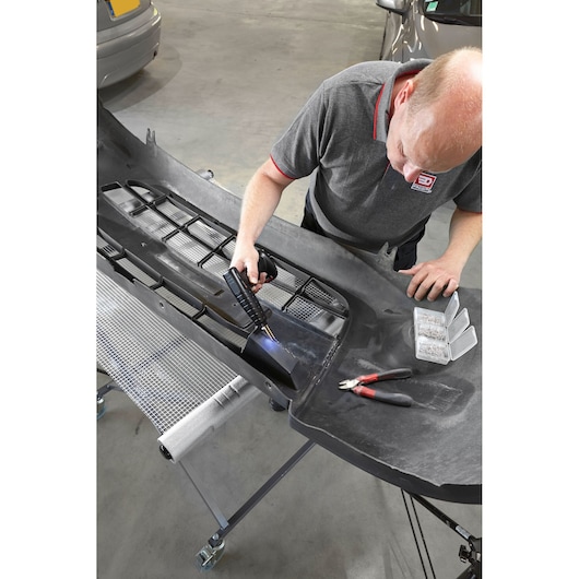 Facom CRPSC photography of technician using repair tool on black car bumper in workshop.