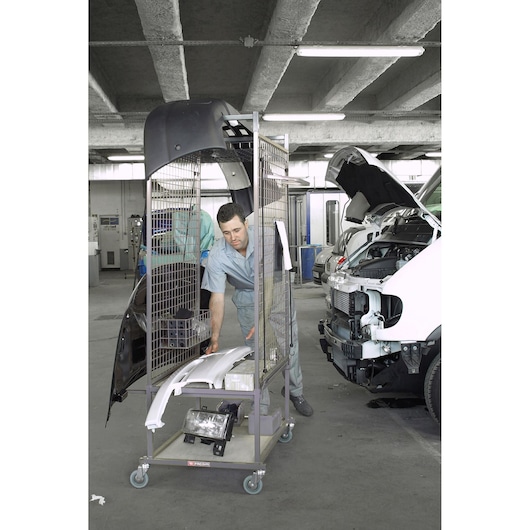Facom CRS1 metal rolling cart with car parts, photographed in an auto repair garage next to cars being serviced.