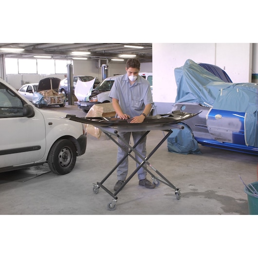 Facom CR_S7 folding workshop stand with wheels, holding car parts in an automotive repair garage.