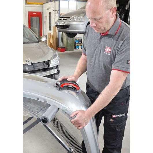 Facom CR_SBS sanding block held by technician working on car body panel in workshop.