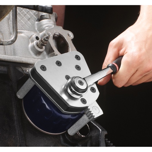 Facom D151A adjustable oil filter wrench in use on automotive engine part, close-up photography.
