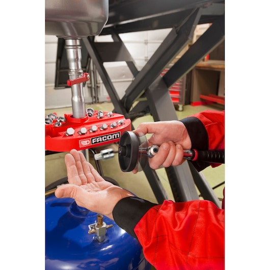Photo of Facom D_48-KIT air tool kit in use, technician holding pneumatic tool under workshop lift.