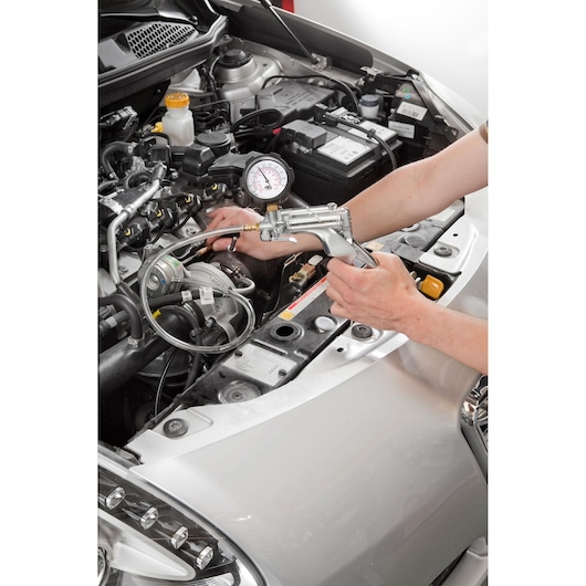 Facom DA_160 automotive diagnostic tool used on car engine, photography showing hands operating the device.