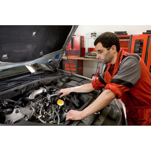Facom DCRIP photography of mechanic using ratchet wrench on car engine in workshop.
