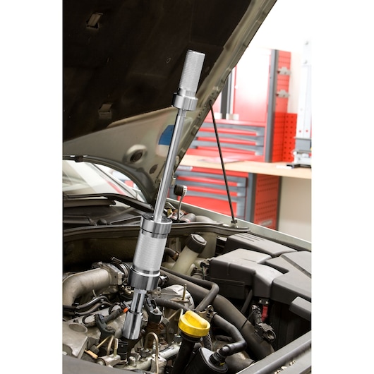 Facom DCRIP automotive slide hammer tool in use on engine block, garage workshop background.