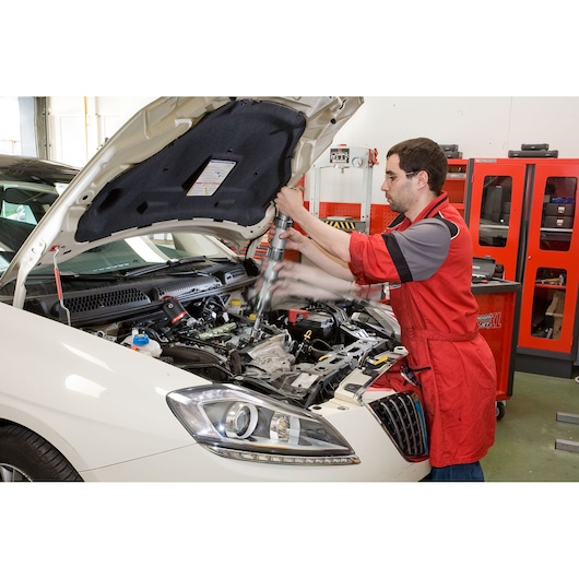 Facom DCRIP photography of mechanic using tool on car engine in workshop.