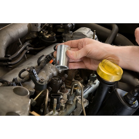 Facom DCRIP socket tool held above engine, showing automotive usage, close-up photography.