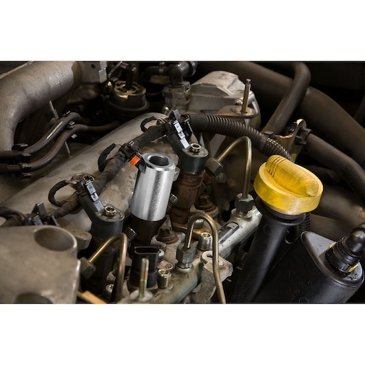 Facom DCRIP socket tool used on a car engine, close-up photo showing automotive context.
