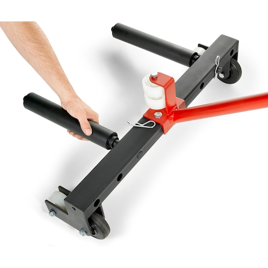 Close-up of a trolley-type photography equipment with wheels, red and black metal frame, and a hand adjusting a cylindrical black attachment.