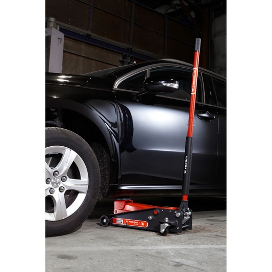 Facom DL.32APB hydraulic floor jack lifting black car, red and black design, workshop setting.