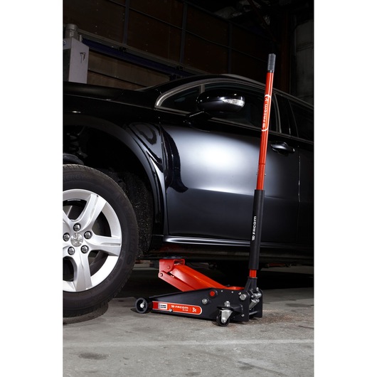 Facom DL.32APB trolley jack lifting black car in garage, red and black handle visible.