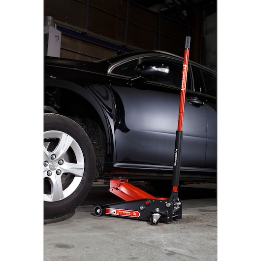 Photo of Facom DL.32APB hydraulic floor jack lifting a black car, red and black design, side view.